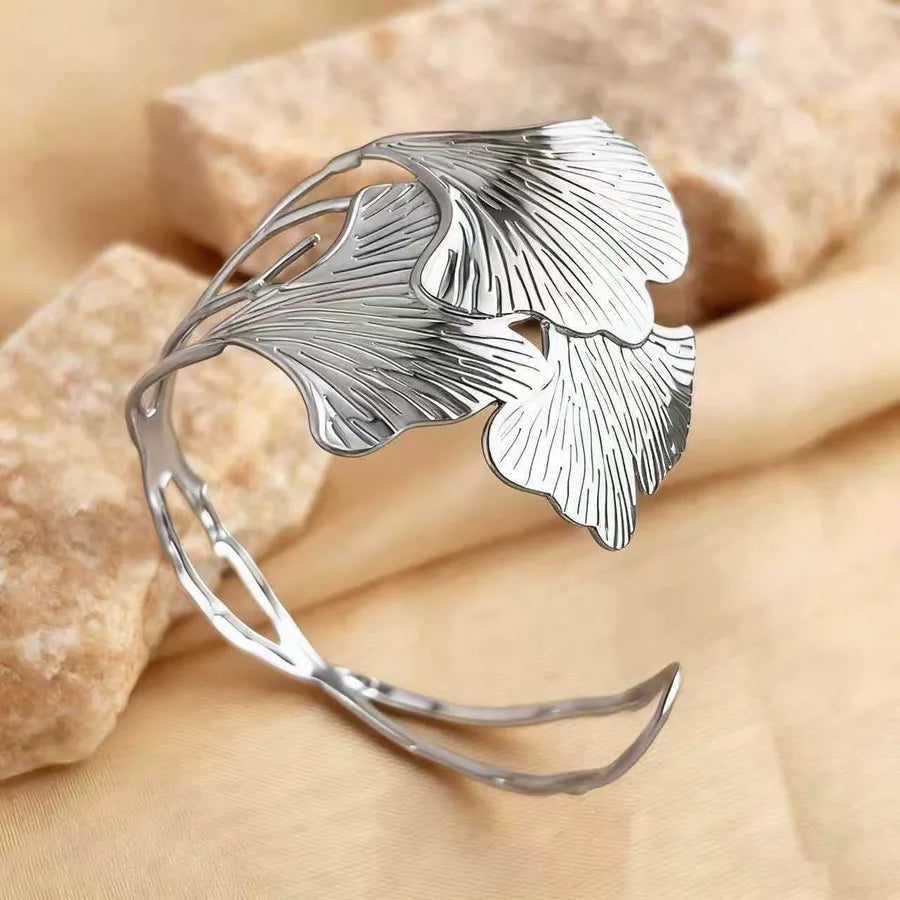 Silver leaf-shaped bracelet on a beige stone background