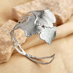 Silver leaf-shaped bracelet on a beige stone background